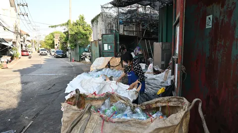 Pracownik na ulicy w Pattaya sortuje plastikowe butelki do wielkich worków typu big-bag przy punkcie skupu surowców wtórnych.