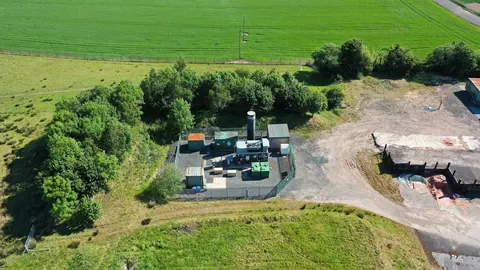 Instalacja odgazowania składowiska Betton Abbots z lotu ptaka: pochodnia i kontenery technologiczne wśród zieleni i pól.