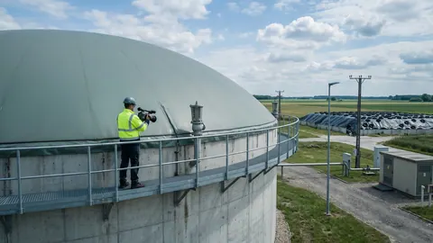 Inspektor z kamerą OGI na pomoście zbiornika fermentacyjnego z dachem dwumembranowym, sprawdza zawór nad- i podciśnieniowy i obrzeże membrany.