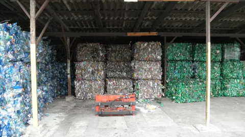 Bele butelek PET posortowanych według koloru – niebieskie, przezroczyste i zielone – pod wiatą zakładu recyklingu w Ołomuńcu.