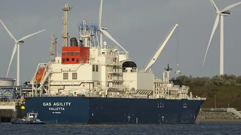 Statek do bunkrowania LNG przy nabrzeżu w porcie Rotterdam, w tle turbiny wiatrowe i żurawie przeładunkowe.