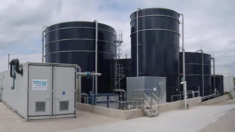 Oczyszczalnia ścieków mleczarskich z bioreaktorem membranowym: ciemne zbiorniki buforowe, reaktory i kontenery technologiczne.
