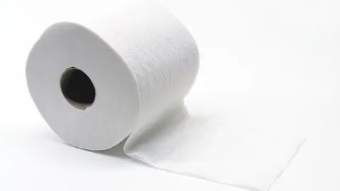 Rolka białego papieru toaletowego z rozwiniętym fragmentem na jasnym tle – przykład odpadów papierów higienicznych.