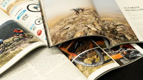 Rozłożone kolorowe czasopisma na stole – kredowany, zadrukowany papier magazynowy z dużymi fotografiami.