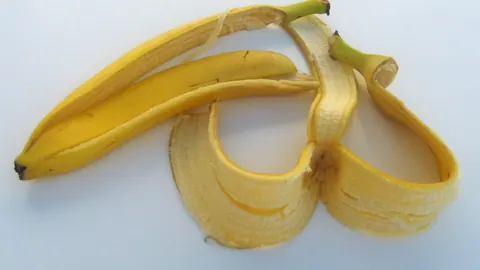 Żółta skórka banana rozłożona w trzy płaty na jasnym tle – typowa pozostałość po zjedzeniu owocu.